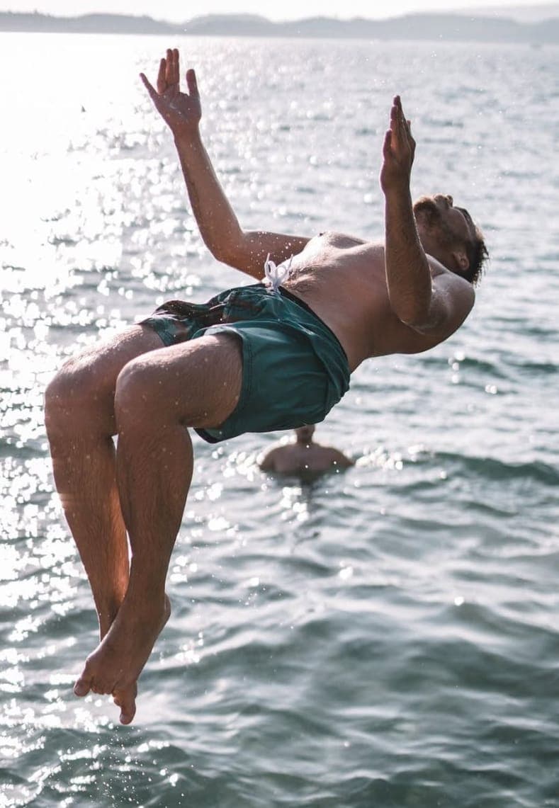 A guest mid-backflip into sparkling water during a swim stop