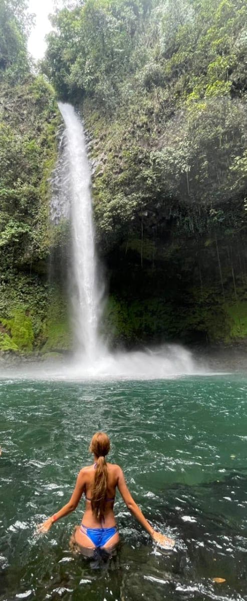 A woman wading into a clear, fast-moving river pool