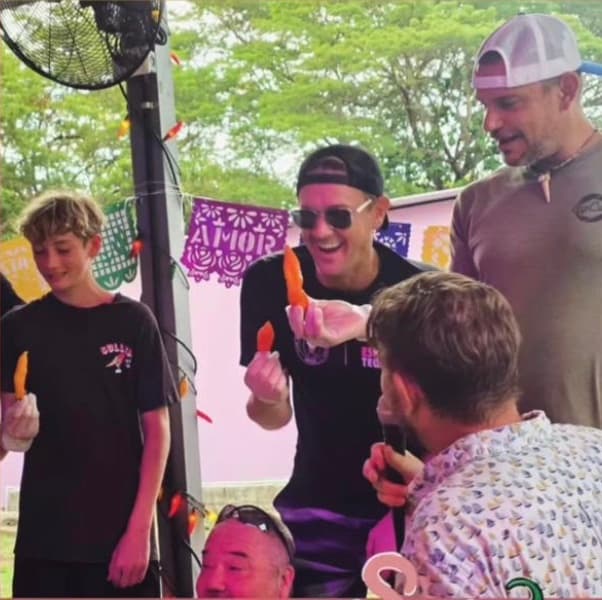Contestants, including a kid, holding up hot peppers at the 2026 pepper-eating contest at Gritanga